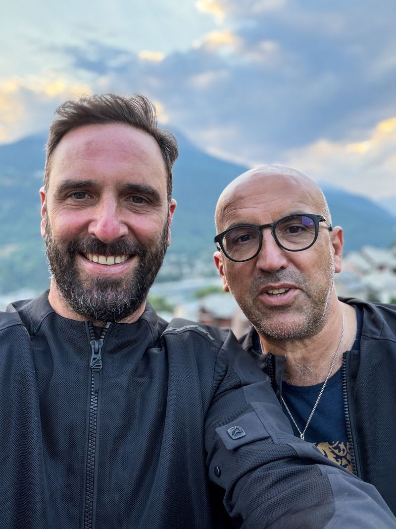 Xavier et Luc Maumon en veste de moto, devant les montagnes de Briançon au coucher du soleil