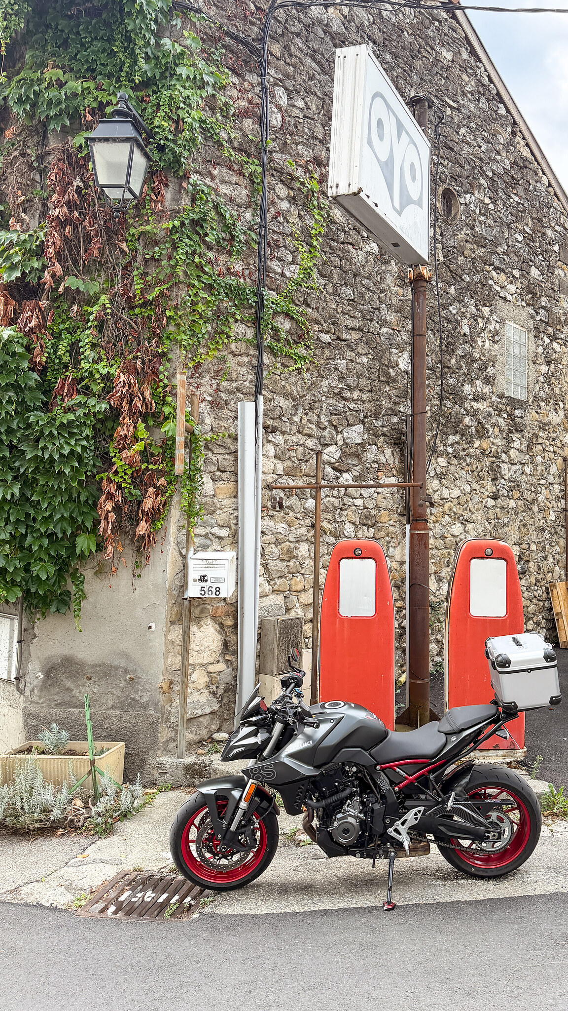 Moto garée devant d'anciennes pompes à essence au Touvet