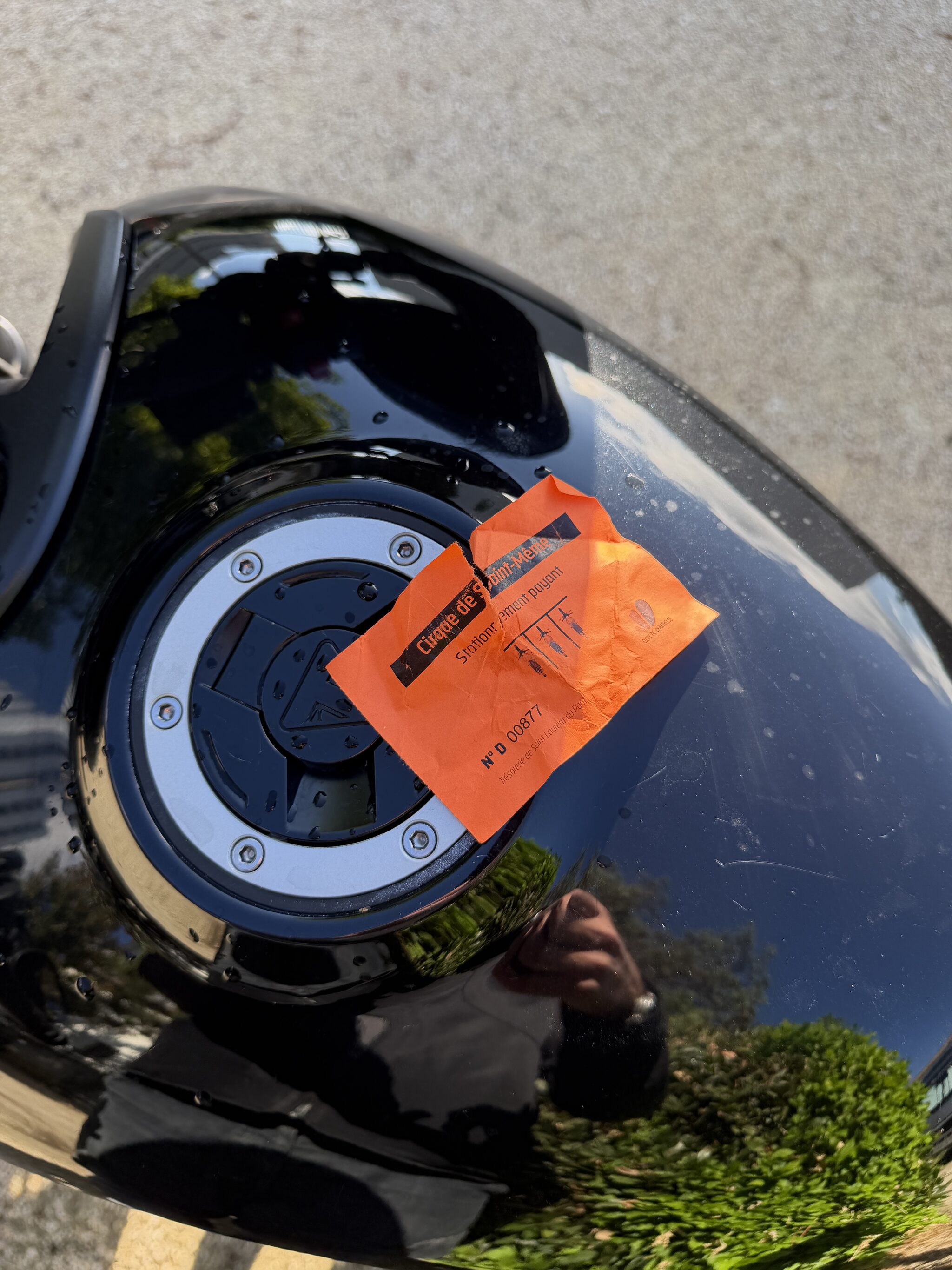 Le ticket de stationnement du cirque de Saint-Même, posé sur le bouchon de réservoir
